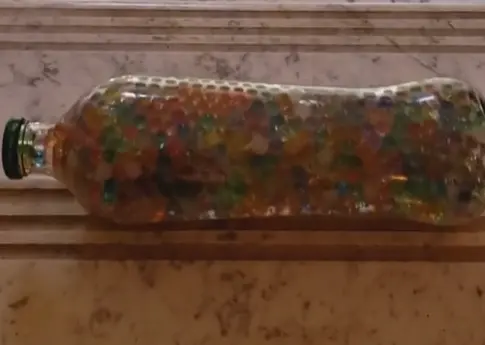 Glass bottle filled with tiny marbles falling down stairs